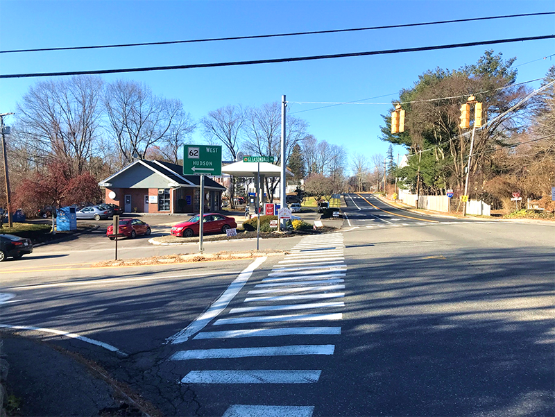 Figure 12 - View across Gleasondale Road (Route 62) of Southwest Intersection Corner. Image shows a long crosswalk that passes to the right of a median and leads to a bed of mulch and vegetation at the perimeter of the gas station parking lot. Figure 12 - View across Gleasondale Road (Route 62) of Southwest Intersection Corner. Image shows a long crosswalk that passes to the right of a median and leads to a bed of mulch and vegetation at the perimeter of the gas station parking lot.